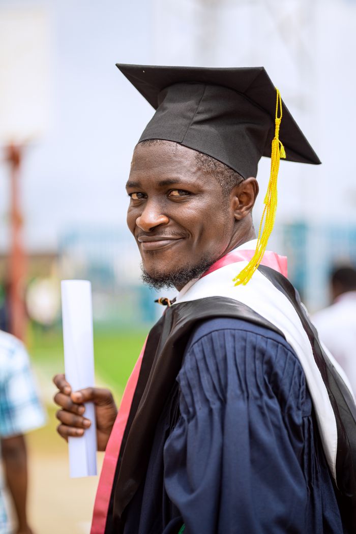 The Art of Drawing Readers In: Your attractive post title goes here Proud graduate holding a diploma, smiling in a cap and gown during a university graduation ceremony outdoors.