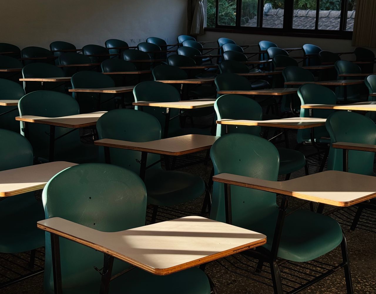 An empty classroom with sunlit desks, evoking a quiet and serene atmosphere.