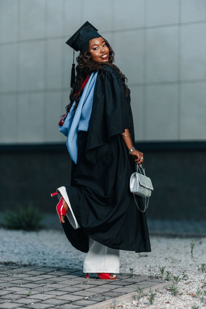 Crafting Captivating Headlines: Your awesome post title goes here Cheerful adult woman in graduation attire celebrating her achievement outdoors.